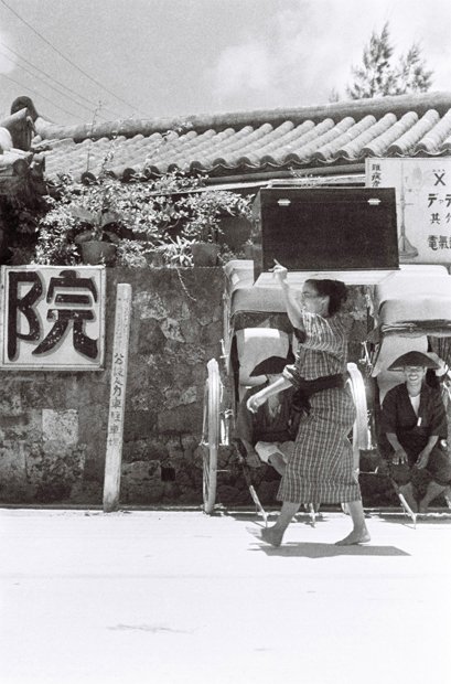 琉球王国時代から使われていた「ケー」と呼ばれた衣装箱を頭に載せて歩く女性。ちょうつがいの形などの細かな作りが本土風に変化している（ｃ）朝日新聞社
