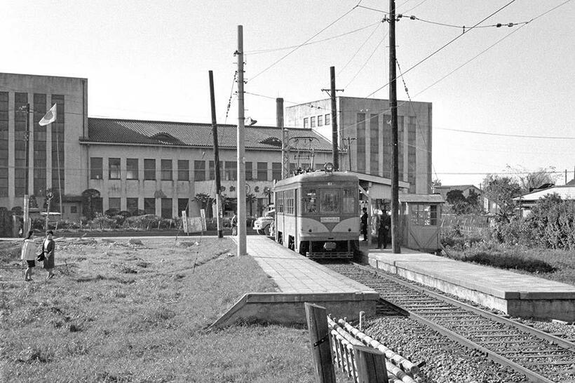 広い構内の砧本村駅で、二子玉川園への発車を待つ砧線の電車。背景は「わかもと製薬」の工場社屋で、現在は駒沢大学玉川キャンパスになっている。（撮影／諸河久：1964年11月3日）