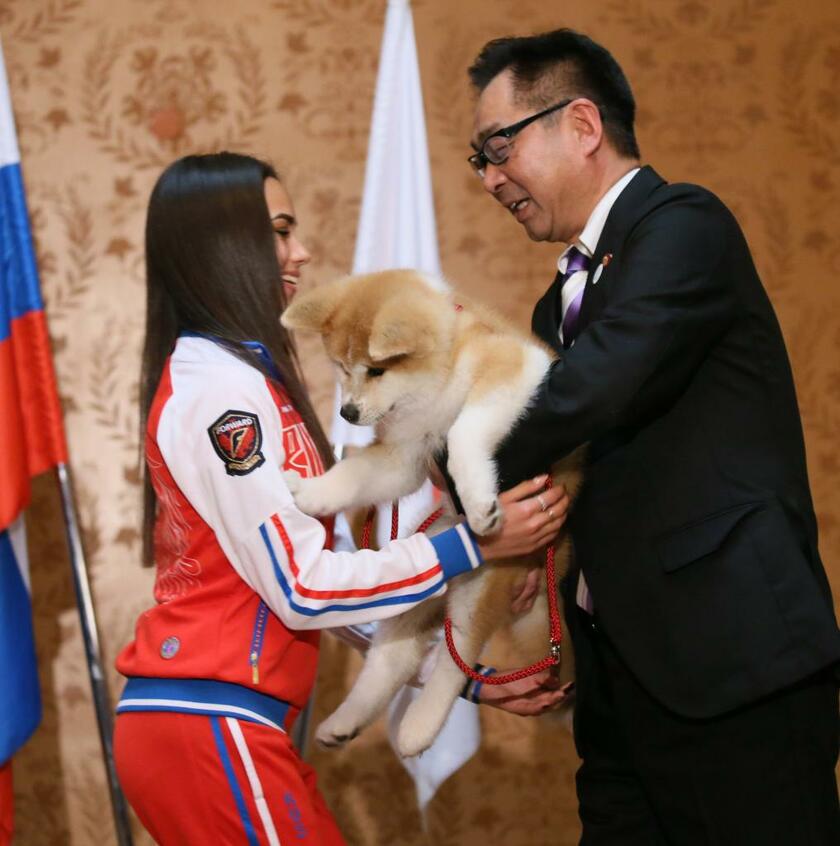 秋田犬保存会の遠藤敬会長（右）から、秋田犬「ＭＡＳＡＲＵ（マサル）」を受け取るロシアのアリーナ・ザギトワ選手