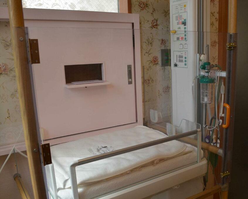 慈恵病院の「こうのとりのゆりかご」。ベビーベッド奥の小さな扉が屋外につながっており、外から預け入れることができる (c)朝日新聞社