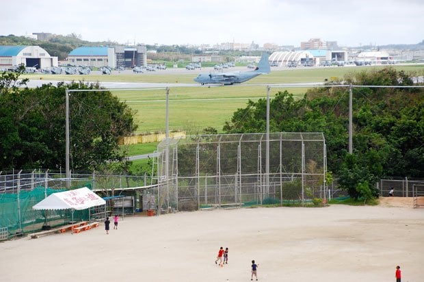 普天間第二小学校のグラウンドで遊ぶ児童たち。普天間飛行場の米軍機が目前に駐機している＝沖縄県宜野湾市の同小学校で。２０１１年、渡辺豪撮影