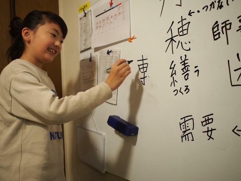自ら研究した漢字の法則について、ホワイトボードに書きながら解説する小林都央さん。疑問に思ったことや頭の中をよく書き出すという＝東京都の自宅で