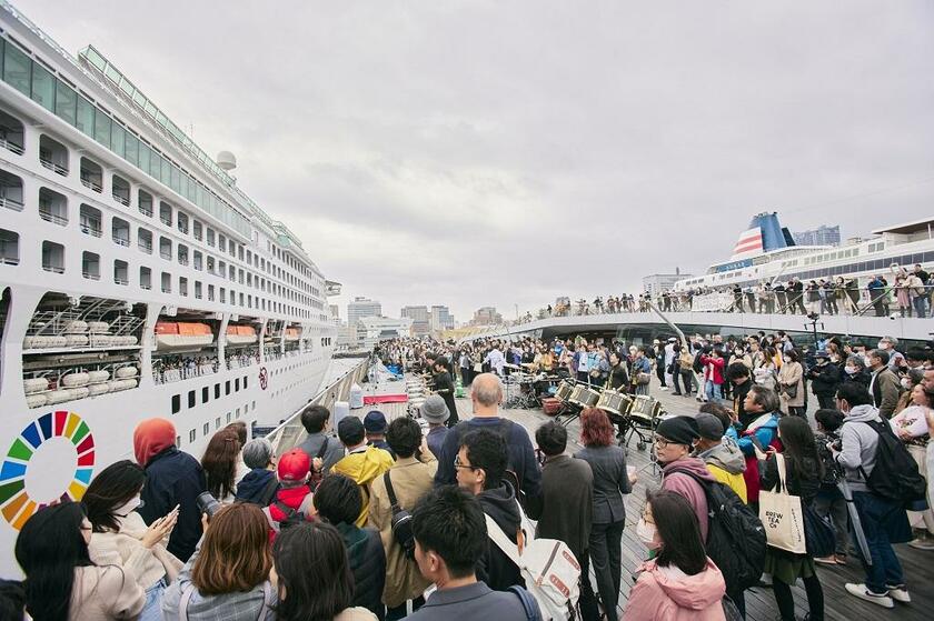 ４月７日、横浜・大さん橋を出航するピースボートの大型客船。家族や友人ら大勢が見送りに集まった。右後方には大型客船「飛鳥ＩＩ」も停泊する（写真：ジャパングレイス提供）