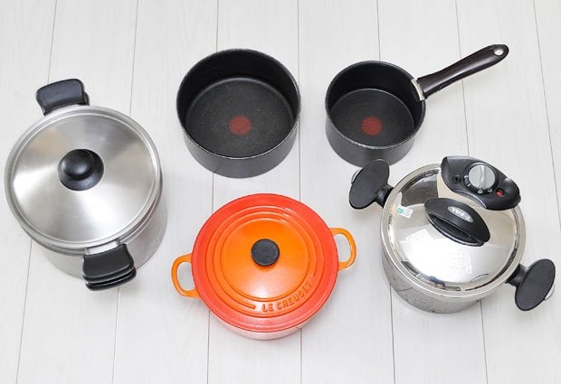 左から、ステンレスの両手鍋（柳宗理のパスタ鍋）、オレンジの鍋は鋳鉄ホーロー鍋（ル・クルーゼ、22センチ）、中が黒い鍋2点は、アルミにフッ素加工を施したティファールの取っ手が取れる鍋（左20センチ、右16センチ）、ステンレスの圧力鍋（ティファール）