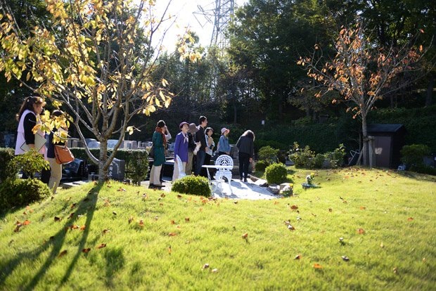 東京都町田市にある、緑豊かな霊園内で一般墓に交じって散在する「桜葬」の墓所を見学する人たち。春には満開の桜の下、桜葬メモリアル（合同祭祀）が開かれる（撮影／関口達朗）