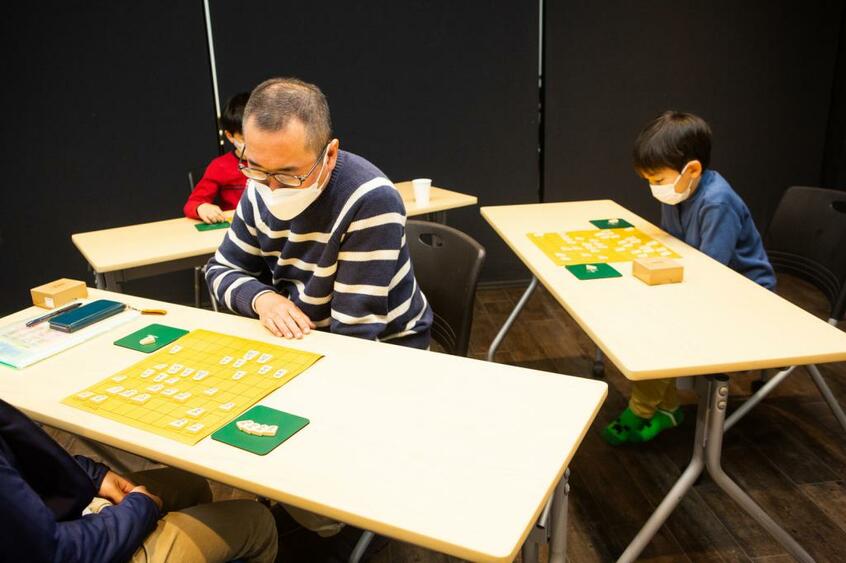 「経堂・ちとふなこども将棋教室」で指導するプロ棋士の高野秀行六段(写真中央)。著書に『こどもをぐんぐん伸ばす「将棋思考」』などがある(撮影/写真映像部・高橋奈緒)