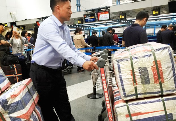 北京首都国際空港で、包装されて中身が分からない大きな荷物を、平壌行きの高麗航空で運ぶためにチェックインする北朝鮮の男性（写真：ｇｅｔｔｙｉｍａｇｅｓ）