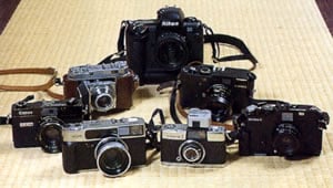 前列右からベッサ-R、オリンパスペンS、コニカヘキサー、2列目にライカM6、レチナⅡa、キヤノンGⅢと愛用のレンジファインダーカメラとクラシックカメラが並ぶ。最近は作品量が膨大になったため、保存・管理を考えてニコンD1で撮るか悩んでいるという