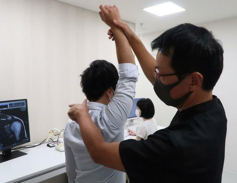 肩の可動域を調べる診察をする菅谷啓之医師　（提供／菅谷医師）