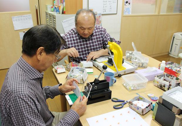 缶バッジ（１個５０円）を作るため、アルミを型でくり抜くような力仕事は主に男性たちが行っている。この日も１００個以上作った（撮影／村田くみ）