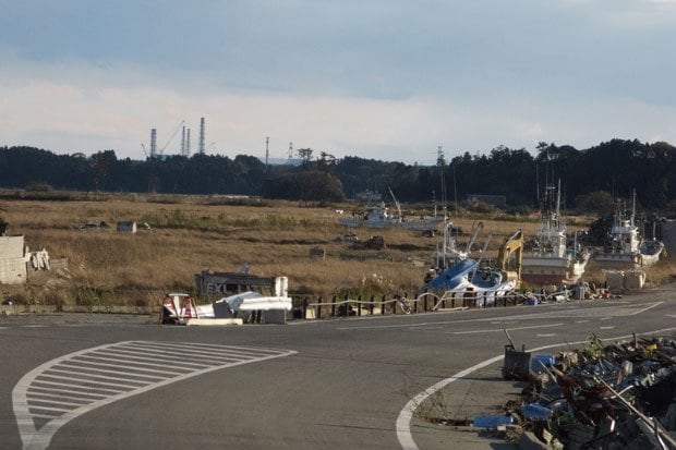 浪江町請戸。６キロあまり先に、東電福島第一原発の排気筒が見える。津波で流された船は、いまだ片付けられていない（撮影／大石芳野）