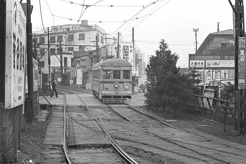 生活感溢れる大塚駅前を走る32系統荒川車庫行きの都電。王子電軌引継ぎの160型が稼働していた。画面手前には大塚駅前折り返し用の分岐器が写っている。向原～大塚駅前（撮影／諸河久：1965年11月23日）