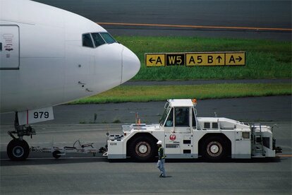 下の写真と同じ撮影位置から、プッシュバック中の機首部分を望遠端でズームアップ。絞り開放は画面周辺部に少し甘さがあり、全体的にもう少しコントラストを上げたいところだが中心部分の描写は思いのほかよい。細身のレンズはワイヤーフェンス越しでも隙間から狙って撮影できるのも利点だ●400ミリ時・ニコンD7500・AE(絞りf6.3・1000分の1秒・-0.3補正)・ISO100・AWB・JPEG
<br />