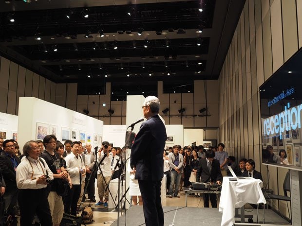 写真展のオープニングレセプション。僕も登壇したのでステージ脇から。TwitterやFacebookには僕の画像がアップされていましたが（笑）。挨拶しているのは元ソニーCEOの出井伸之さん
<br />