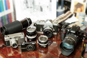 中央がメーンで使っているニコンF。生まれ育った下町の風景を撮り続け、その写真を基に繊細なペン画が生み出される。手前右がフィルムの生産量が減少したため購入したという最初のデジタルカメラ、ニコンCOOLPIX S640。左がコンタックスTVS。いずれも小型軽量でポケットに入れて持ち歩けるのが気に入っている。右は昨年購入した一眼レフのニコンD5100