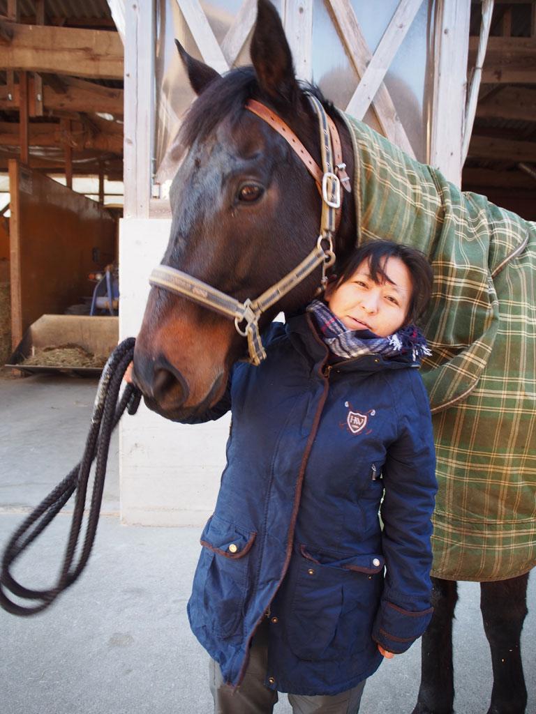 渡部南さん。南相馬市小高区に移住し、１４頭の馬を飼育する。２０１８年夏には地元の男性と結婚。「夜、馬たちが横になってぐっすり寝ているのを見るのが楽しみ」。写真は、被災馬の「おに君」（撮影／編集部・野村昌二）