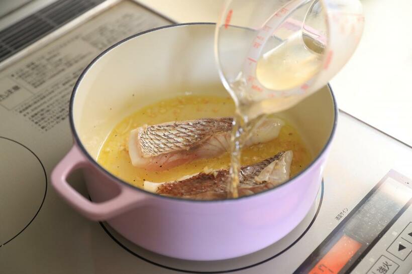 【ワンポイントアドバイス】白身魚を鍋に入れ両面に焼き色をつけ、白ワインをふりかける　（撮影／写真部・松永卓也）