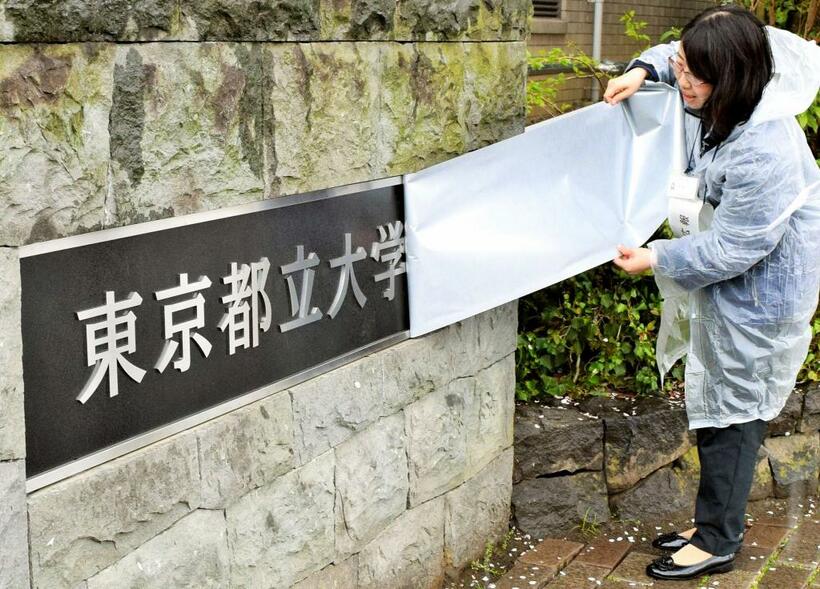 職員が旧校名の覆いをはずすと「東京都立大学」の文字が現れた。東京都立大学南大沢キャンパス南門（2020年4月1日、(c)朝日新聞社）