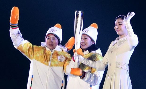 平昌五輪の開会式で南北合同チームとなったアイスホッケー女子「コリア」の韓国、北朝鮮の選手２人からトーチを受け取る聖火最終点火者のキム・ヨナさん　（ｃ）朝日新聞社