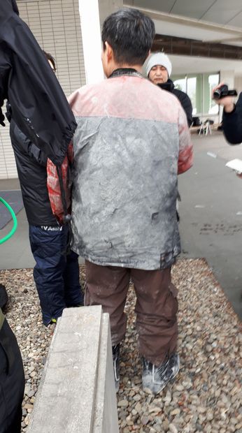 報道陣の取材に答える男性。服の後ろ側は噴石で破れたという　（ｃ）朝日新聞社