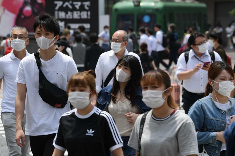 緊急事態宣言の解除後も、マスク姿の人がほとんどだ。渋谷のスクランブル交差点では多くの人が行き交う…（c）朝日新聞社