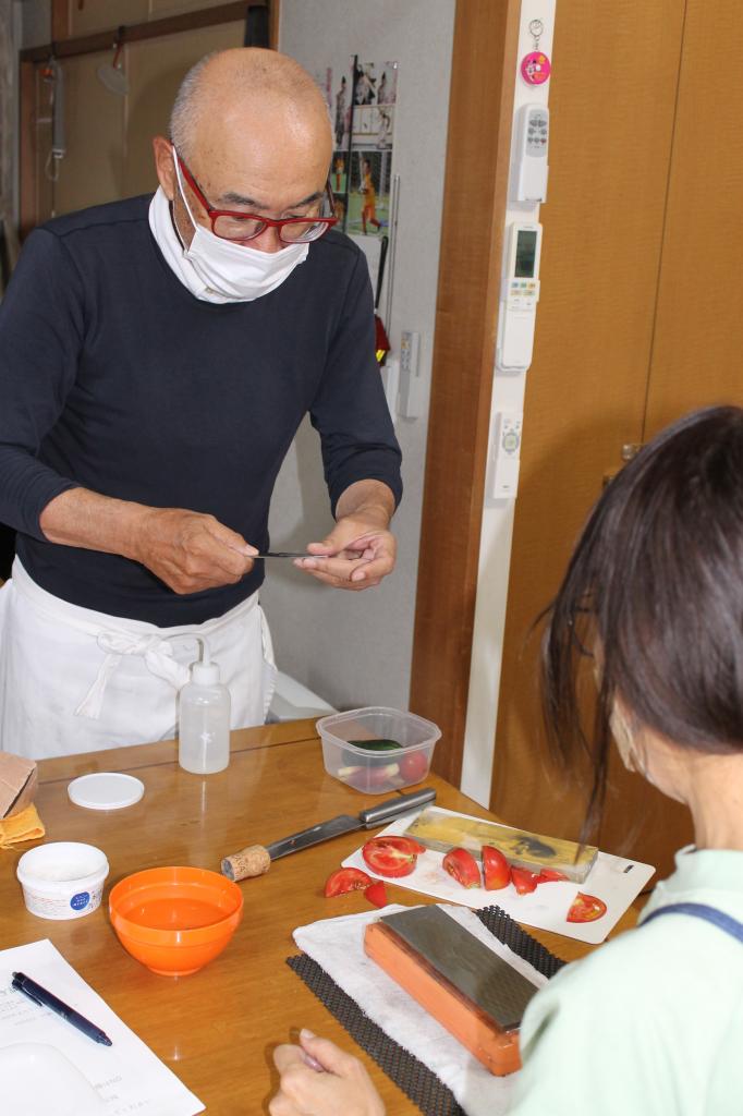 生徒に研ぎ方を教える豊住さん（奥）