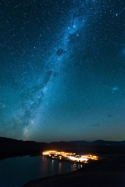 展望台から３６０度見渡せる星空を天の川が貫き、南十字星が光る。「宇宙の姿が感覚的にわかるのがすごいでしょう」と小澤さん。眼下に広がるテカポの町の街灯は、低圧ナトリウム灯で灯火規制されている（撮影／写真部・馬場岳人）