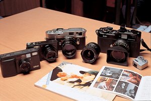 ライカを愛する鎌田さんのカメラは右から、エプソンR-D1、ライカM4、リコーR8、リコーGR21。中央のレンズは、フォクトレンダー ウルトラワイドへリアー12ミリF5.6。手前は右から、KiroroのCD「Wonderful Days」のライナーノーツ、Mizrockの写真集「An Ordinary Days」。いずれも鎌田さんの撮影による