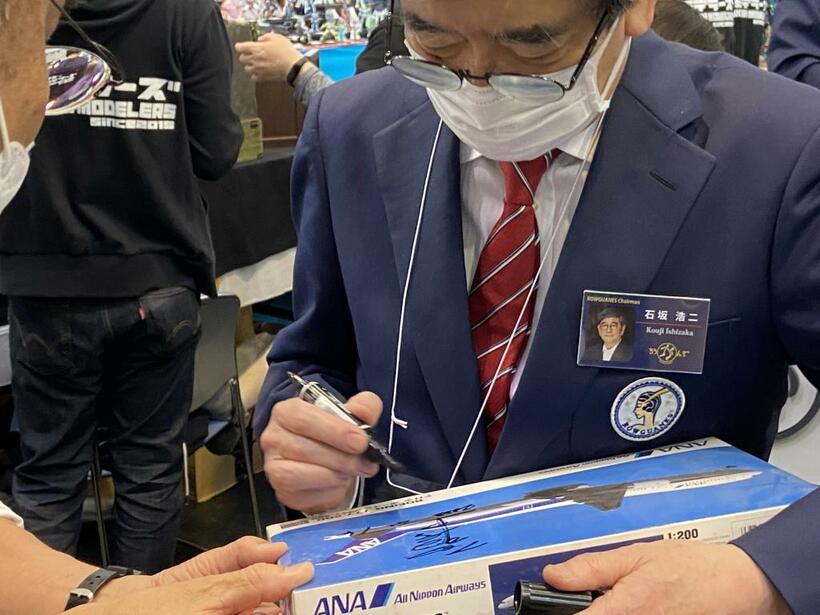 ファンが持参した飛行機プラモの箱にサインをする石坂浩二さん