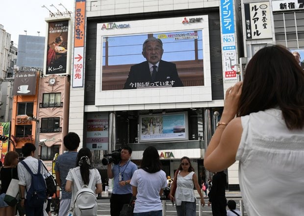 街頭の大画面で天皇陛下のお気持ちを示したビデオメッセージが流され、通りかかった人たちが見上げていた　 （ｃ）朝日新聞社