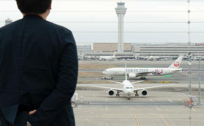 渡航制限が拡大し運休が相次ぐ羽田空港。数少ない利用者が、機体に書かれた「ＴＯＫＹＯ２０２０」の文字を見つめる（撮影／小山幸佑）