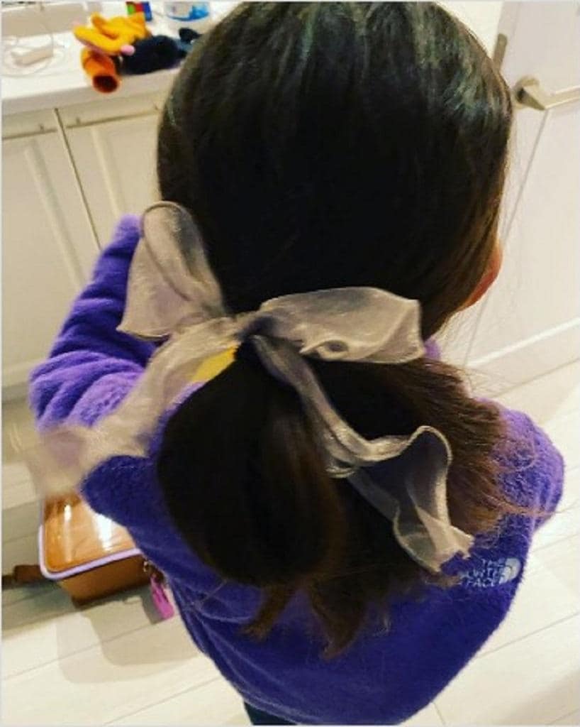 娘さんの髪をアレンジ。リボンのついたゴムに四苦八苦するも、娘さんは「めっちゃ良い」(2022年12月、山根さんのInstagramより)