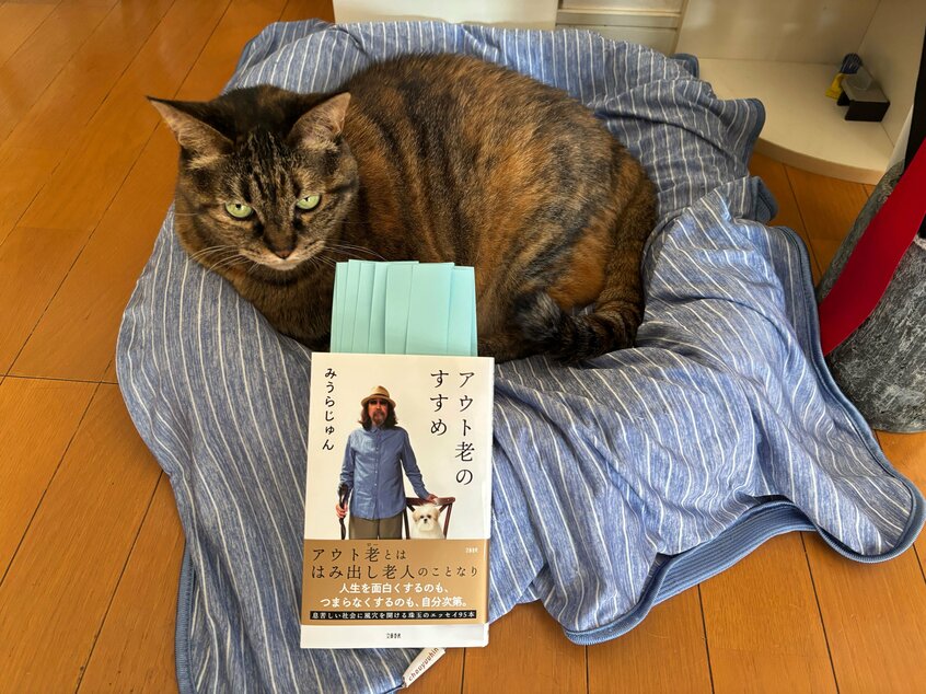 みうらじゅんさんの近著『アウト老のすすめ』。同著で「老いるショック」のワードが出てくる箇所に付箋を貼ってみた。見守るのは、オンライン取材が途切れた直後にソファに嘔吐した自宅の老ネコ(撮影・渡辺豪)