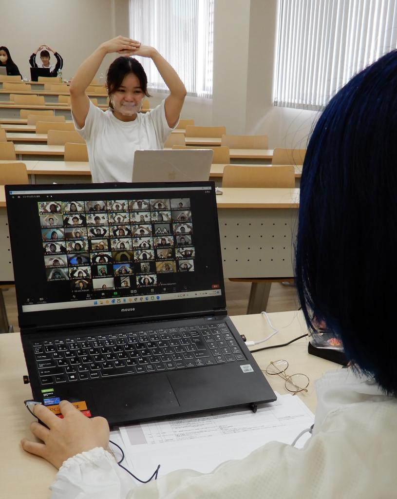 コロナ対策で教室の四隅に散り、オンライン会議の〇×ジェスチャーをする若者大会参加者(名桜大学で)(撮影/三山喬)