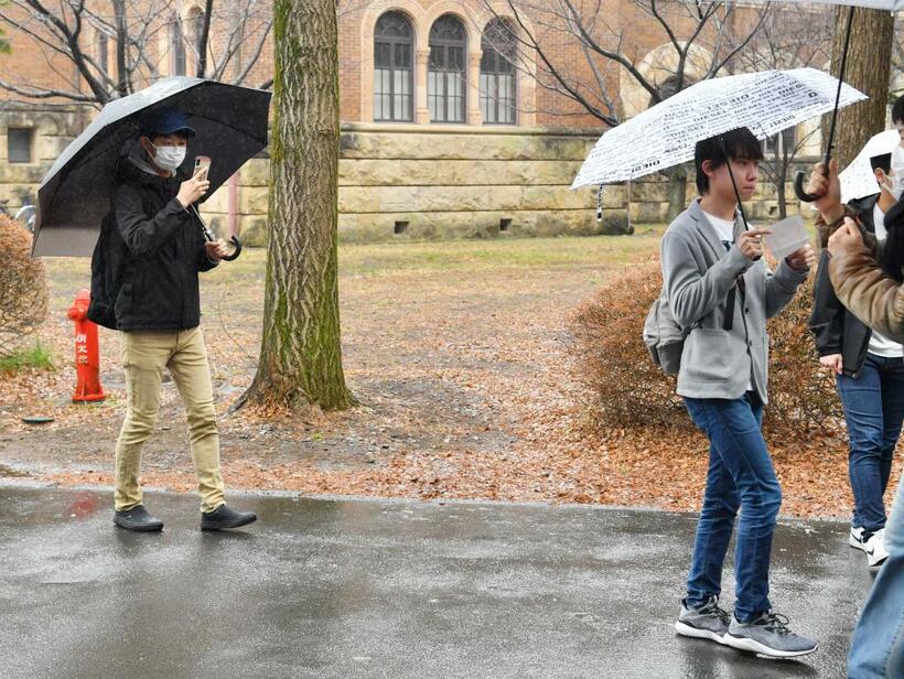 冷たい雨の降るなか、東京・多摩地区にある国公立大学で合格発表に同行する。依頼者から、受験番号を見に行く様子を動画撮影してほしいと頼まれた。この時間、胴上げや万歳をする姿は特に見られなかった（撮影/東川哲也）