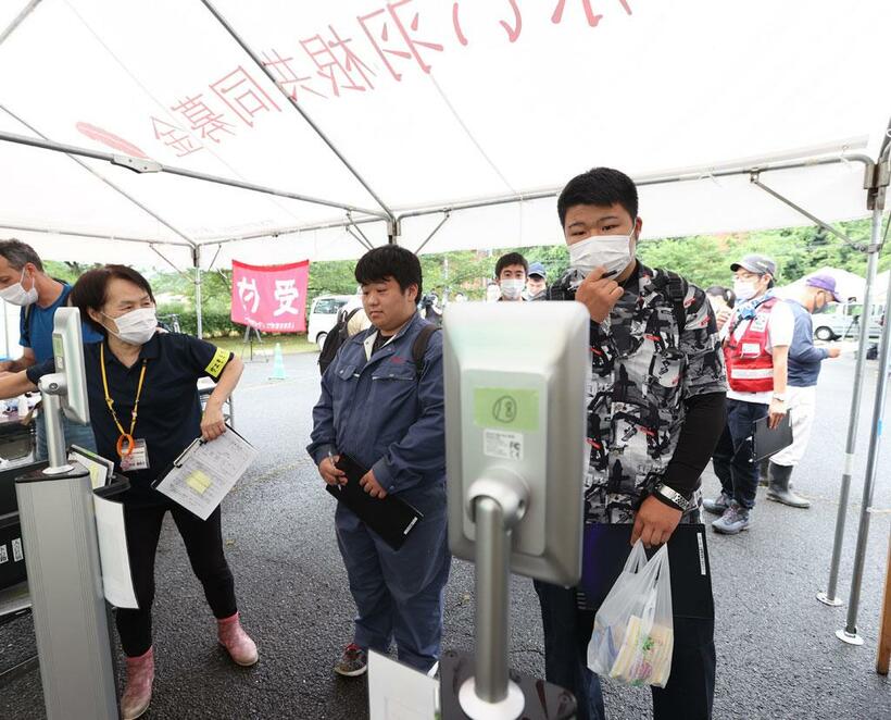 人吉市東間コミュニティセンターでは、ボランティアに訪れた人たちが受付時にマスクを着用して検温した／7月10日、熊本県人吉市　（ｃ）朝日新聞社