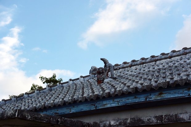 沖縄伝統の赤瓦屋根の上に立つ魔よけのシーサー。カミンチュのＫさんが面談場所に指定した沖縄本島中部の住宅街近くで目に留まった（撮影／編集部・渡辺豪）