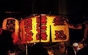 浅草・鷲神社の酉の市の客でにぎわう屋台。「夜の写真が多いですね」と聞いたら、「そのまま飲みに行くからね」と笑った