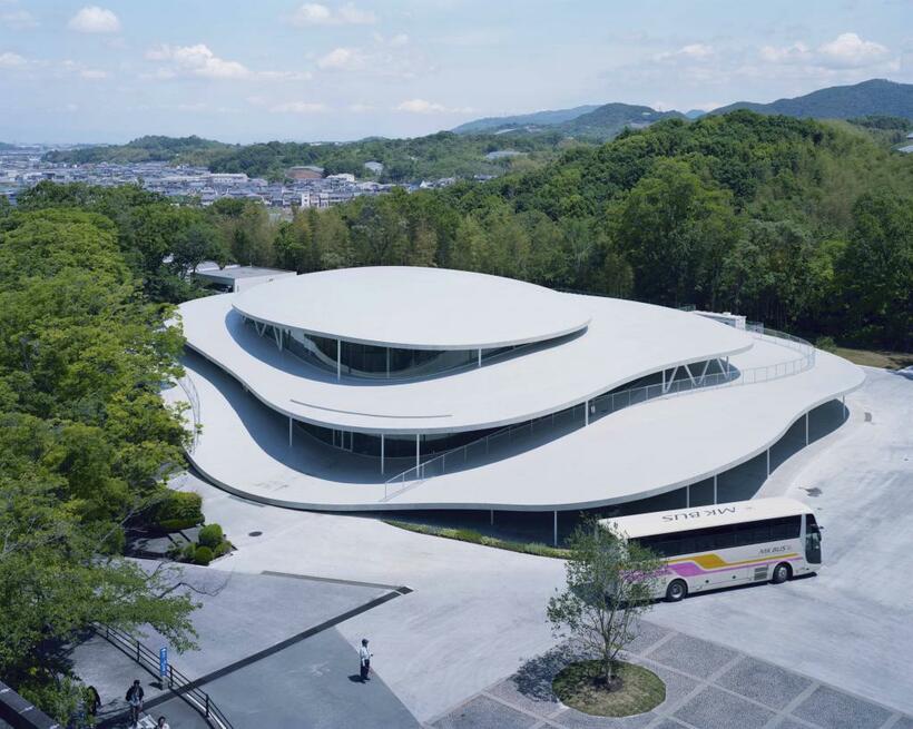 「建築と時間と妹島和世」より、2018年11月に完成した大阪芸術大学のアートサイエンス学科校舎。キャンパスへと続く坂道を上がり、最初に目に入る建物だ。アートサイエンス学科は同大学に2017年に新設。アートと科学を融合し、新しい時代のクリエイターを育てていく