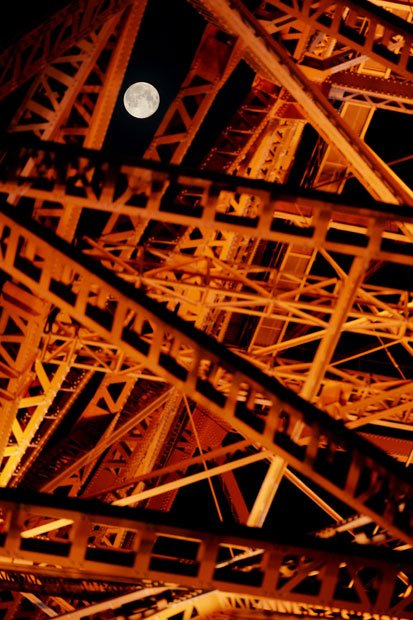 ライトアップされた東京タワーの鉄骨の間にのぞく満月。東京タワーは、満月の夜だけ上部のライトアップをやめて、月を愛でやすくするという粋な計らいもしている（撮影／伊ケ崎忍）