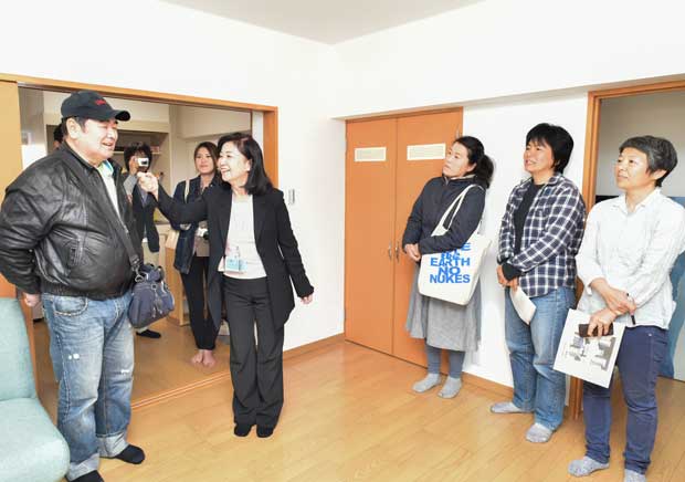 サ高住のモデルルームで、山中敏江さん（右から４番目）の説明を聞く交流グループのメンバー。見学後、アンケートに「こんな暮らし方がしたい」という要望をびっしり書いた（撮影／工藤隆太郎）