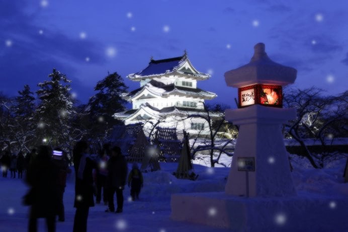 雪の中でライトアップされる弘前城。