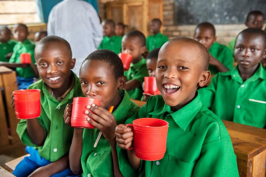 ルワンダ国内の難民キャンプの学校に通う子どもたち。85％がコンゴ民主共和国の難民の子で、残りが地元ルワンダの子ども。トウモロコシと大豆の粉を溶かしたおかゆにニッコリ。日本のように何品も料理は出てこないが、必要な栄養が取れるように計算されている。2015年から学校給食がスタート！　（ｃ）Mayumi Rui