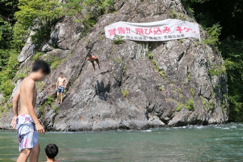 東京都青梅市の多摩川。警告にもかかわらず、岩から飛び込む人が絶えない。ここは水深が深いうえ、川底に引き込む流れがある＝米倉昭仁撮影