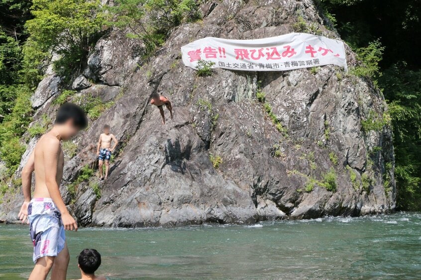 東京都青梅市の多摩川。警告にもかかわらず、岩から飛び込む人が絶えない。ここは水深が深いうえ、川底に引き込む流れがある=米倉昭仁撮影