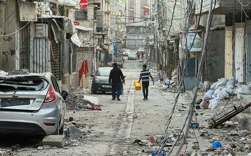 戦闘が一時停止されている11月26日、イスラエルの攻撃によって破壊されたガザ市のビーチ・キャンプの家々の間を歩く人々(写真・ロイター/アフロ)