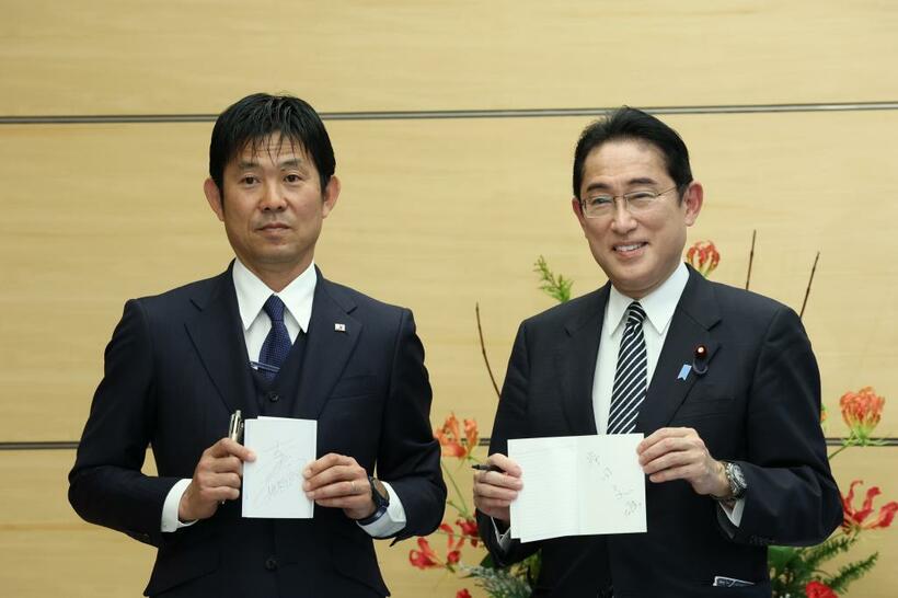 サッカー日本代表の選手たちの表敬訪問を受け、森保一監督（左）とノートを交換する岸田文雄首相。大会期間中は森保監督のメモが“デスノート”と話題を集めた