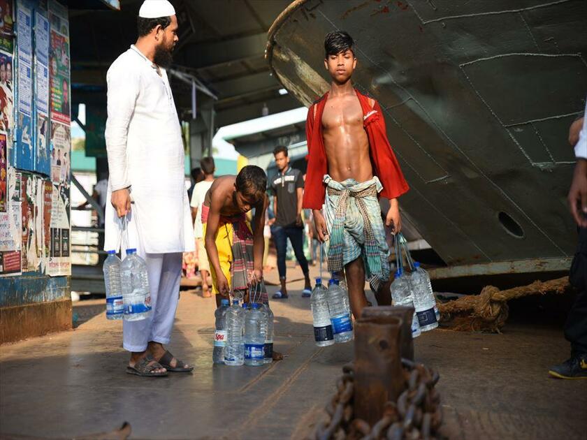 バングラデシュの港で乗船客に水を運ぶ少年たち。非正規の工場や路上では、大人に交じって働いている子どもたちは多い（写真／清水匡）