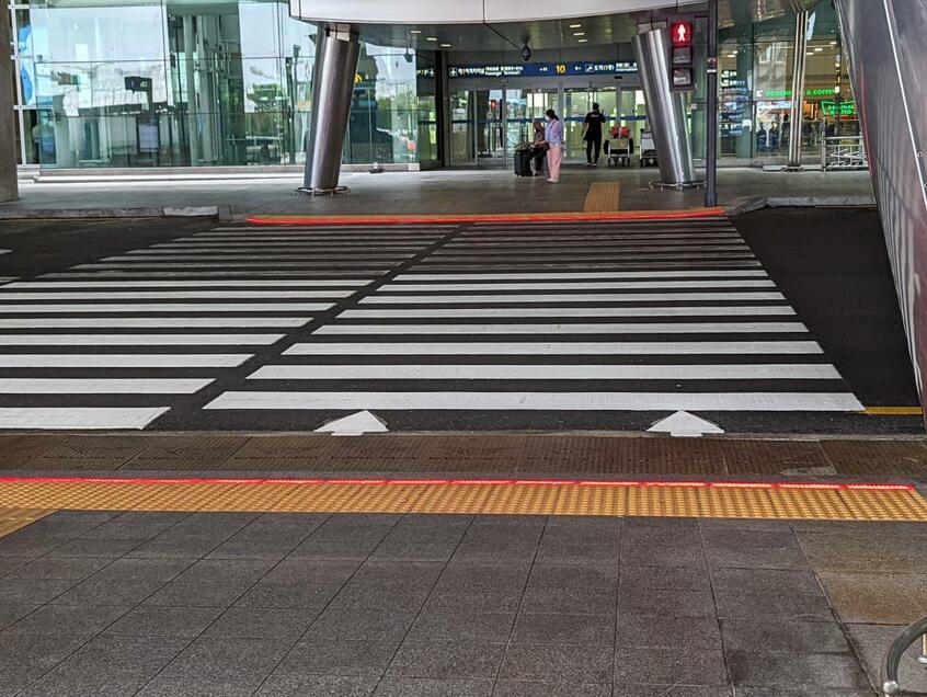 信号機に連動して足元のLEDライトが光る新型の横断歩道。横断歩道の向こうの信号は赤。足元も赤だ