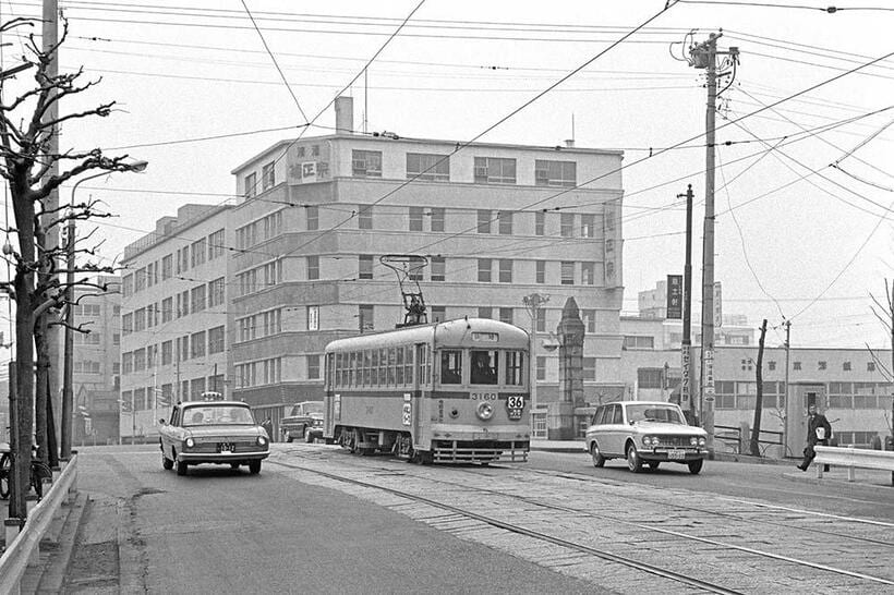 1925年に竣工した築地橋を渡る36系統築地行きの都電。趣のある橋柱の背後が松竹キネマの本社屋だった築地菊栄ビル。その左隣が京橋税務署の旧庁舎で、新庁舎が2021年に竣工している。新富町～築地二丁目（撮影／諸河久：1966年2月16日）